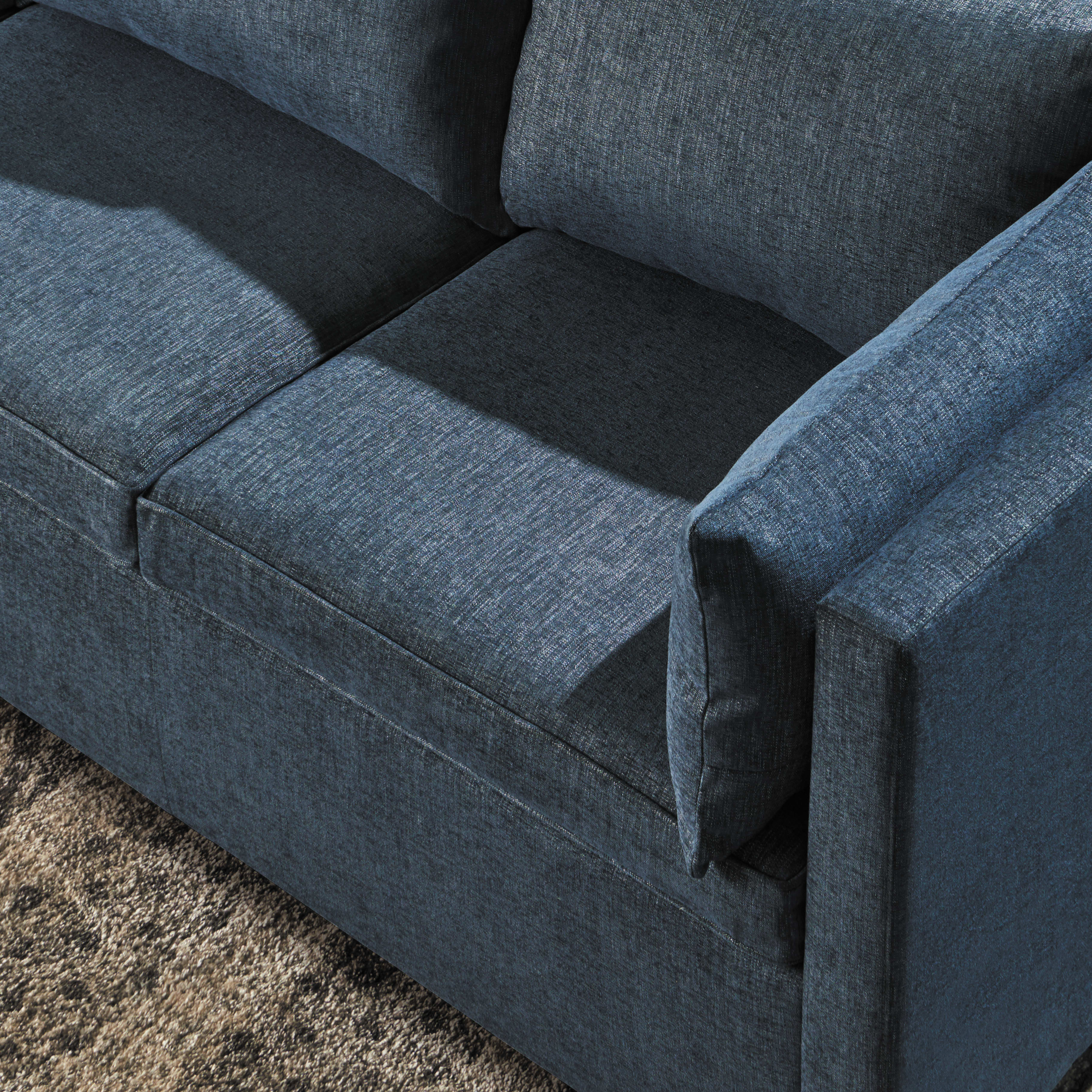 A dark gray upholstered sofa with distinct cushions and armrests sits on a carpeted floor.