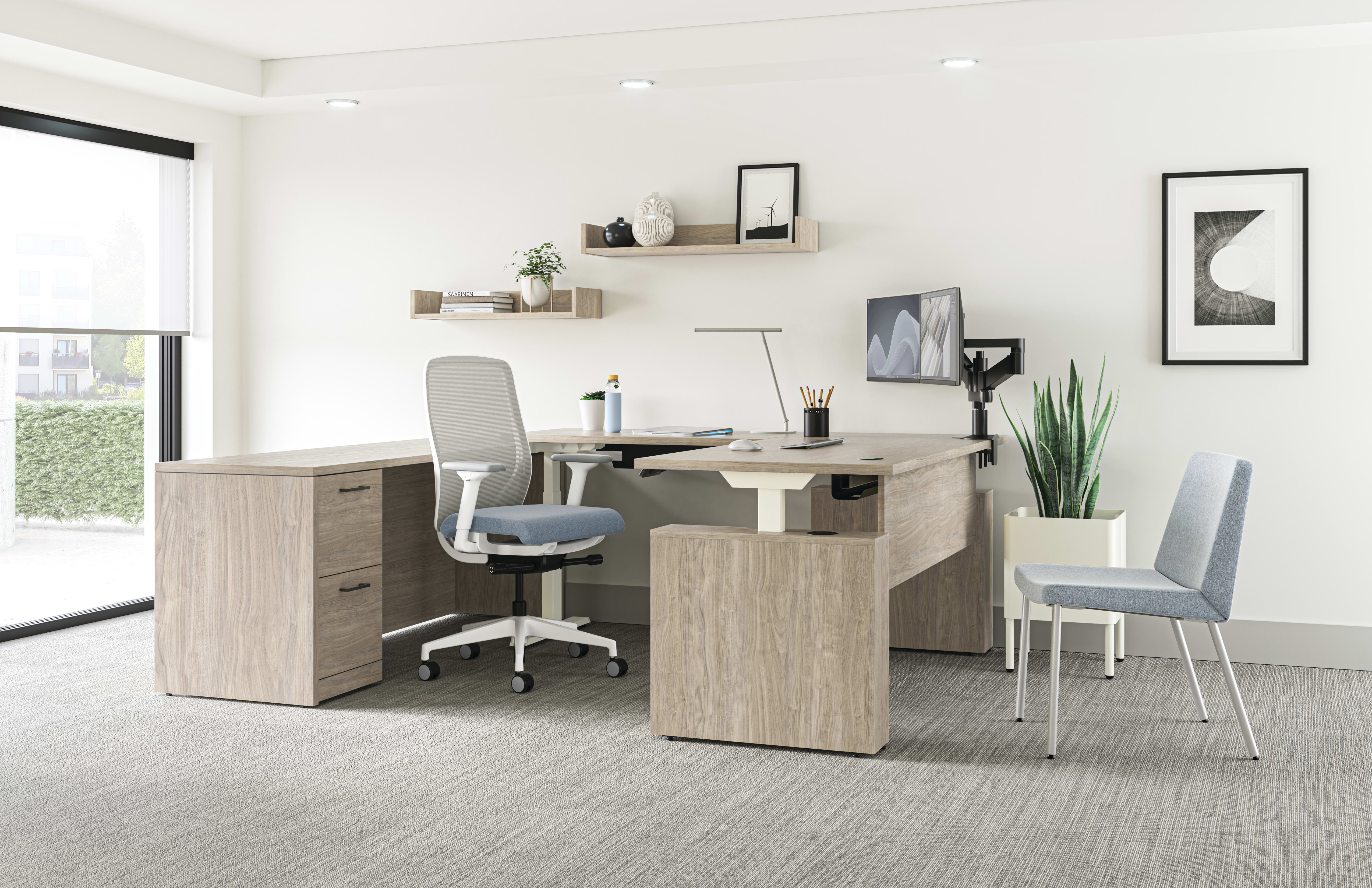 A modern and minimalist home office space with a wooden desk, a gray office chair, and various decorative elements such as shelves, plants, and framed artwork on the walls.