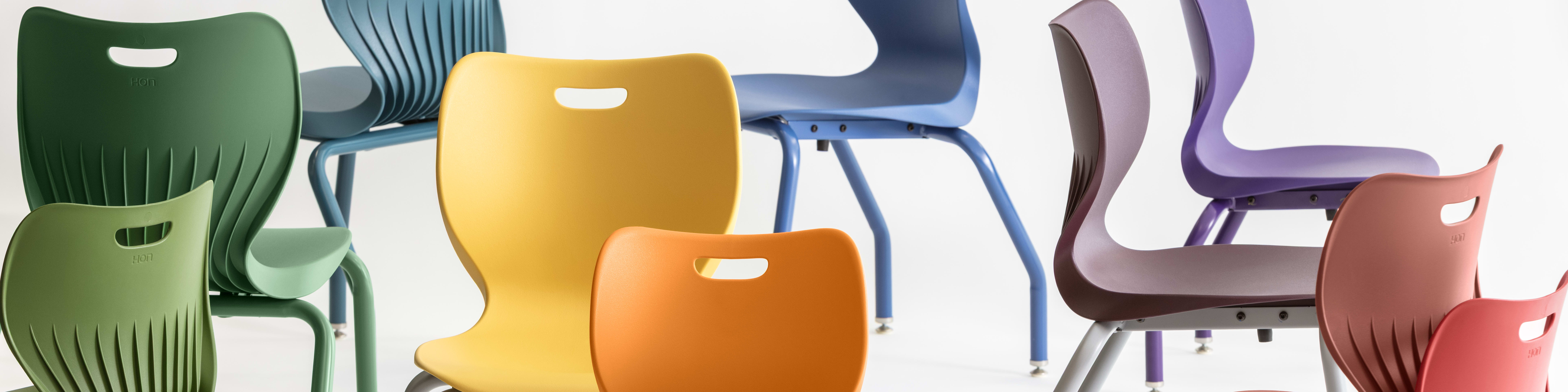 A collection of colorful, modern chairs in various shades of green, blue, yellow, and red, arranged against a plain white background.
