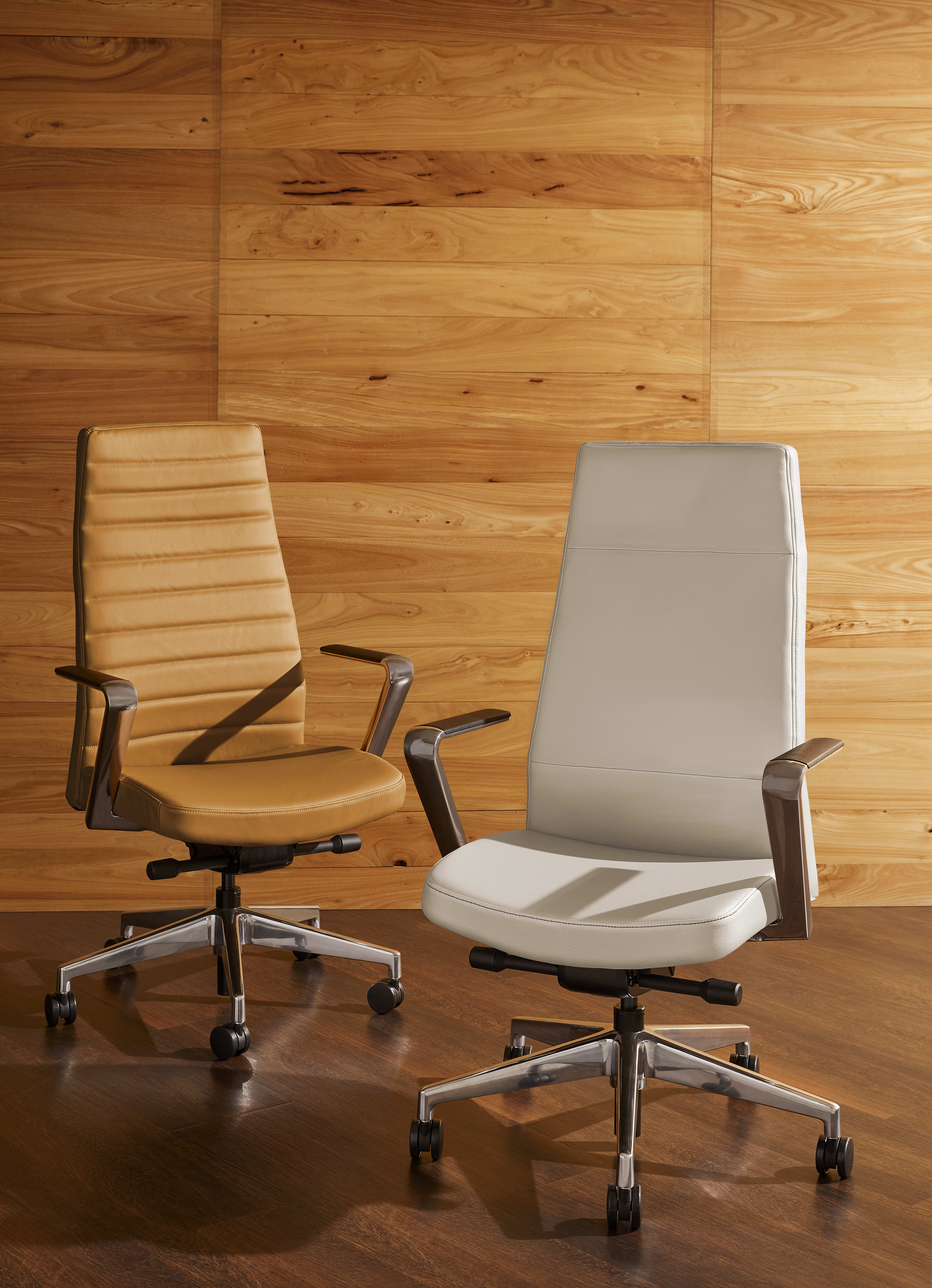 Two modern office chairs with ergonomic designs sit in front of a wooden wall, creating a minimalist and professional workspace environment.