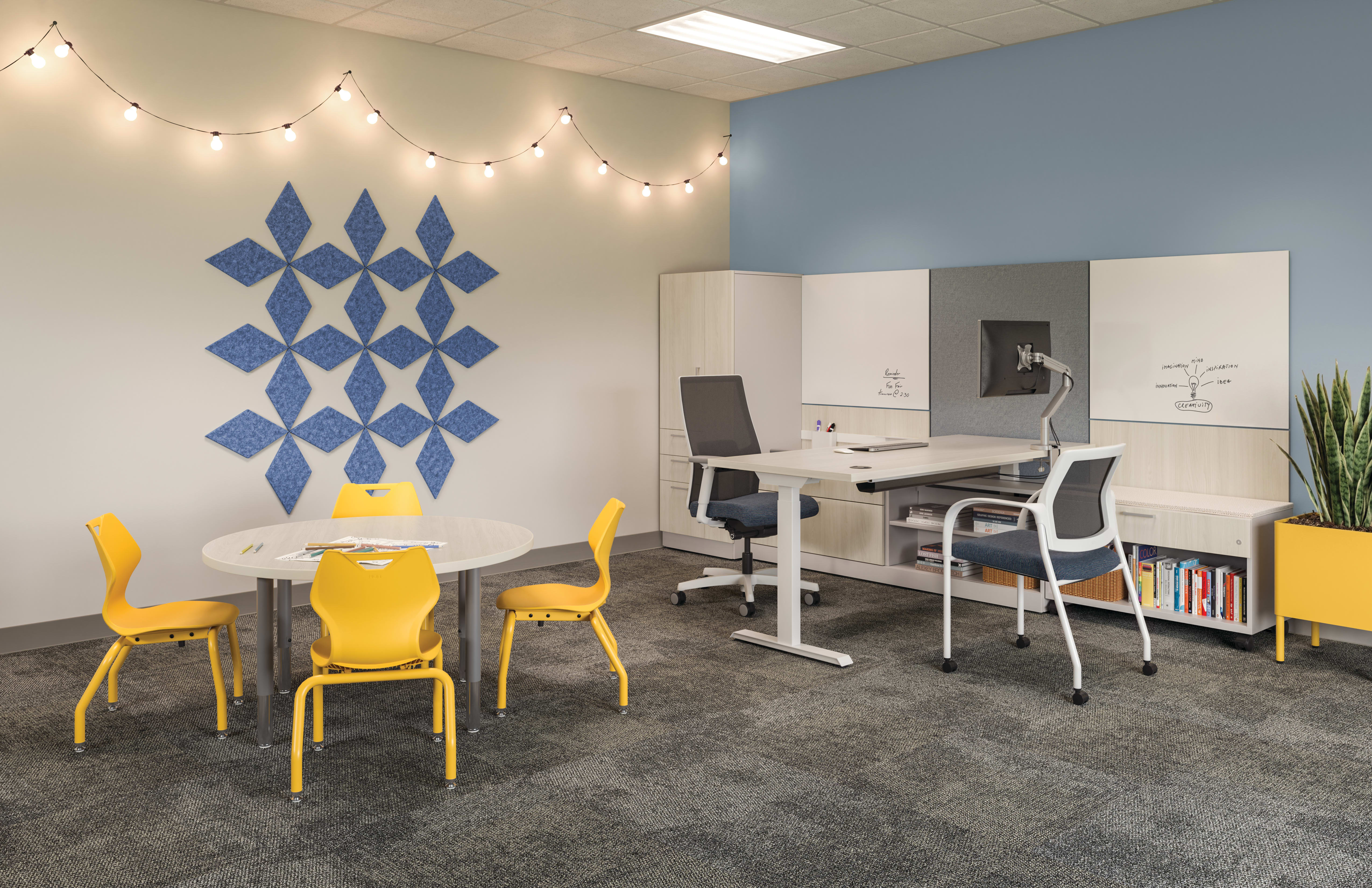 School guidance counselor office with light wood desk and storage, blue acoustic wall panels, whiteboard surfaces, yellow student chairs around a round table, and yellow planter in a collaborative meeting space.