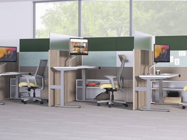 A modern, open-plan office space with multiple workstations, each equipped with a computer monitor, desk, and ergonomic chairs. The large windows in the background provide natural lighting and a view of the surrounding greenery.