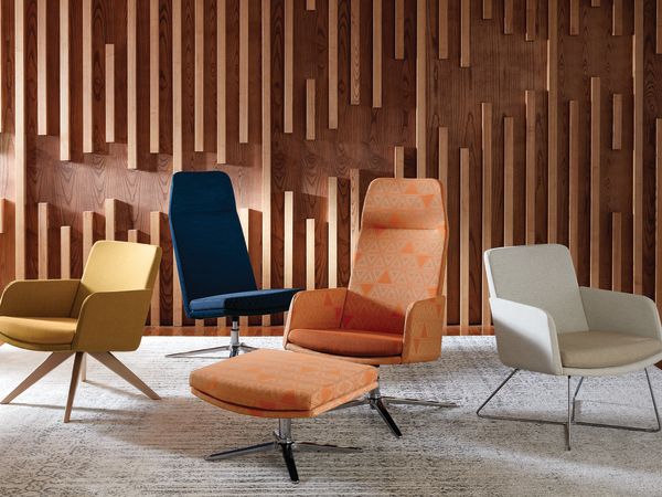 A collection of modern, colorful chairs and ottomans arranged in a room with a striking wooden wall feature.