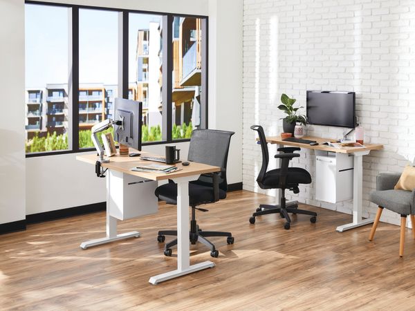 Two white Coordinate Height-Adjustable Bases paired with Coze desk tops and Convergence Task chairs in a small office setting