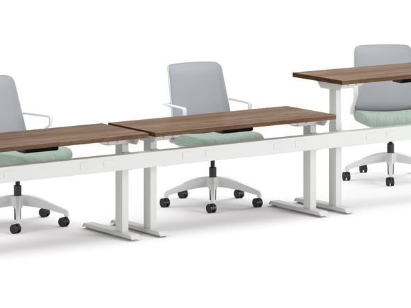 Three ergonomic office chairs positioned behind adjustable-height desks with white frames and wooden tops.