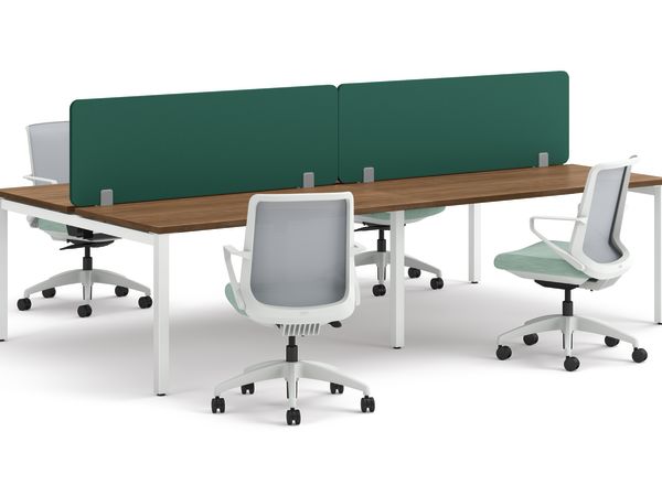 Four ergonomic office chairs positioned around two connected desks with wooden tops, white legs, and green fabric privacy panels.