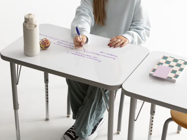One student writing on the whiteboard top of a Build rectangle top desk.