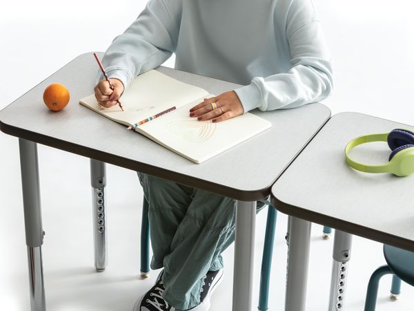 One student writing on the whiteboard top of a Build rectangle top desk.