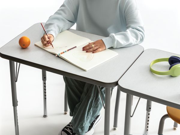 One student writing on the whiteboard top of a Build rectangle top desk.