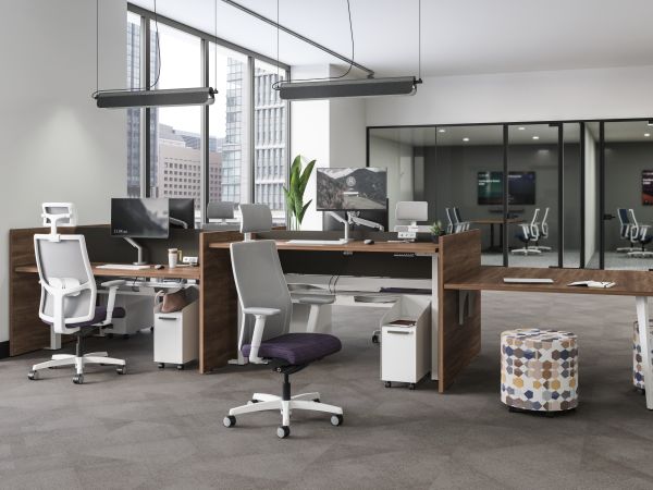 A modern and minimalist office space with desks, chairs, and various office equipment, surrounded by large windows providing natural light and a view of the exterior.