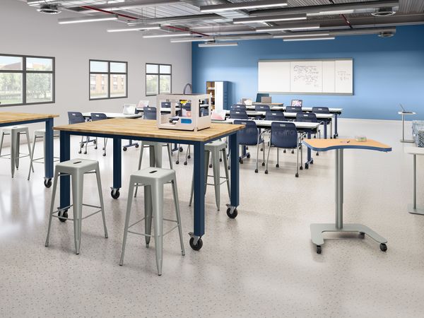 Modern STEM classroom with mobile student desks, high worktables, lab stools, 3D printer workstation, collaborative seating, whiteboard instruction area, and flexible learning zones in a technology-focused educational environment.