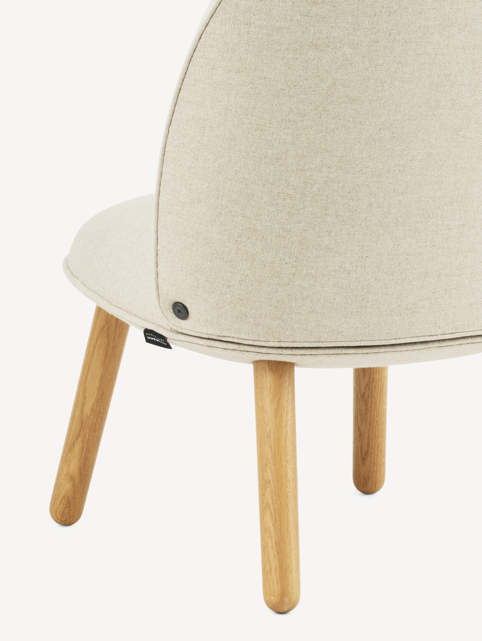 Close-up back view of the Normann Copenhagen Ace lounge chair with light wood legs and off-white upholstery.