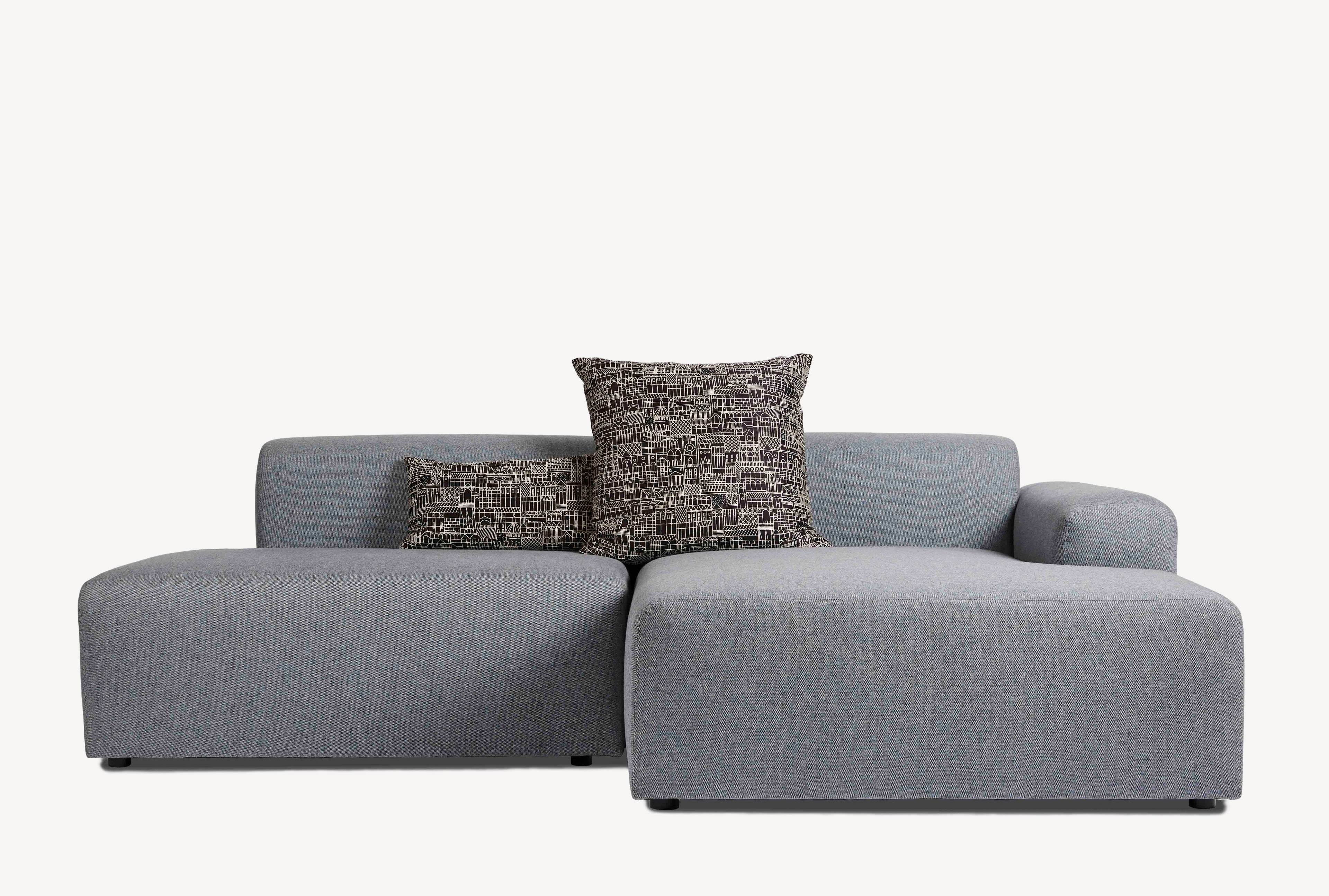 Front view of the Corral Grove modular sofa in grey fabric with two throw pillows.