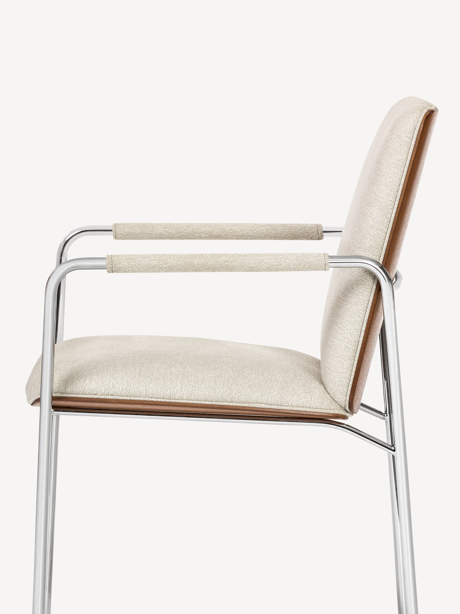 Side view of the Gunlocke Metta guest armchair with silver frame, front upholstered in off-white fabric with off-white upholstered arm pads and wood back.