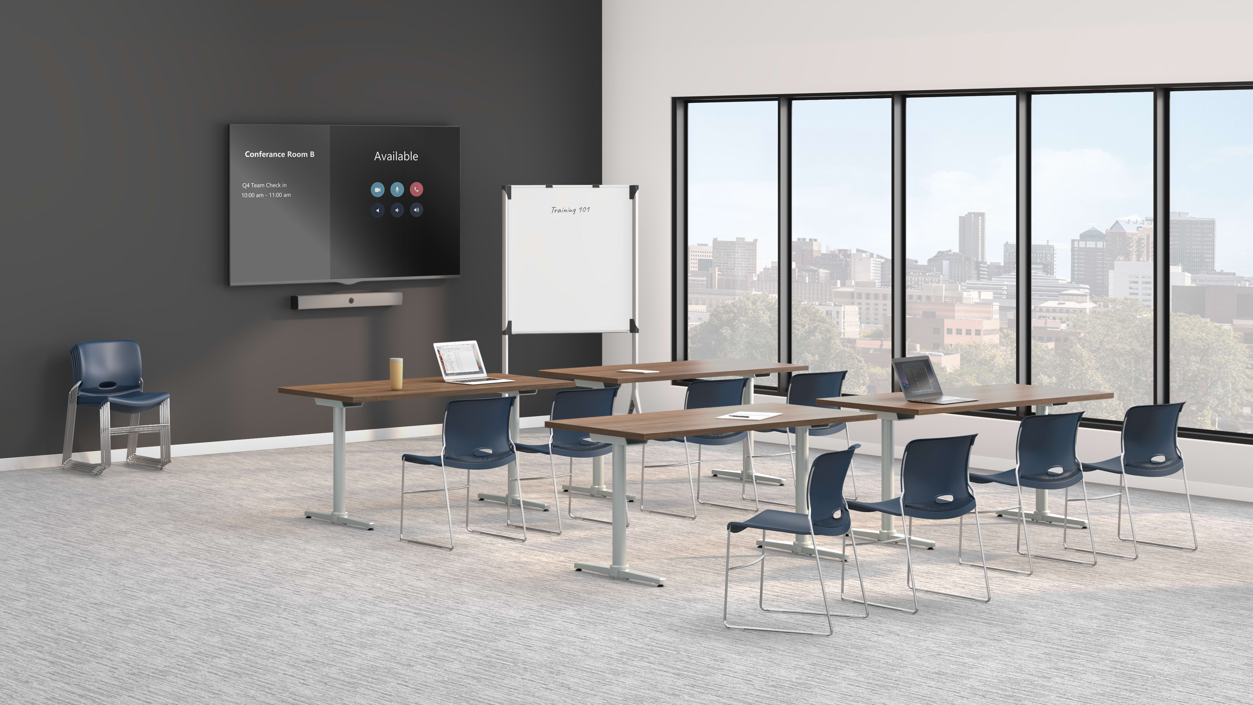 A modern training room with long tables, blue chairs, a wall-mounted display screen, a whiteboard, and large windows overlooking a city skyline.