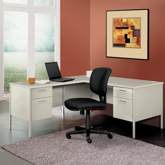 A modern home office setup with a white desk, a black office chair, and a framed abstract artwork on the wall, set against a warm-toned wall color.