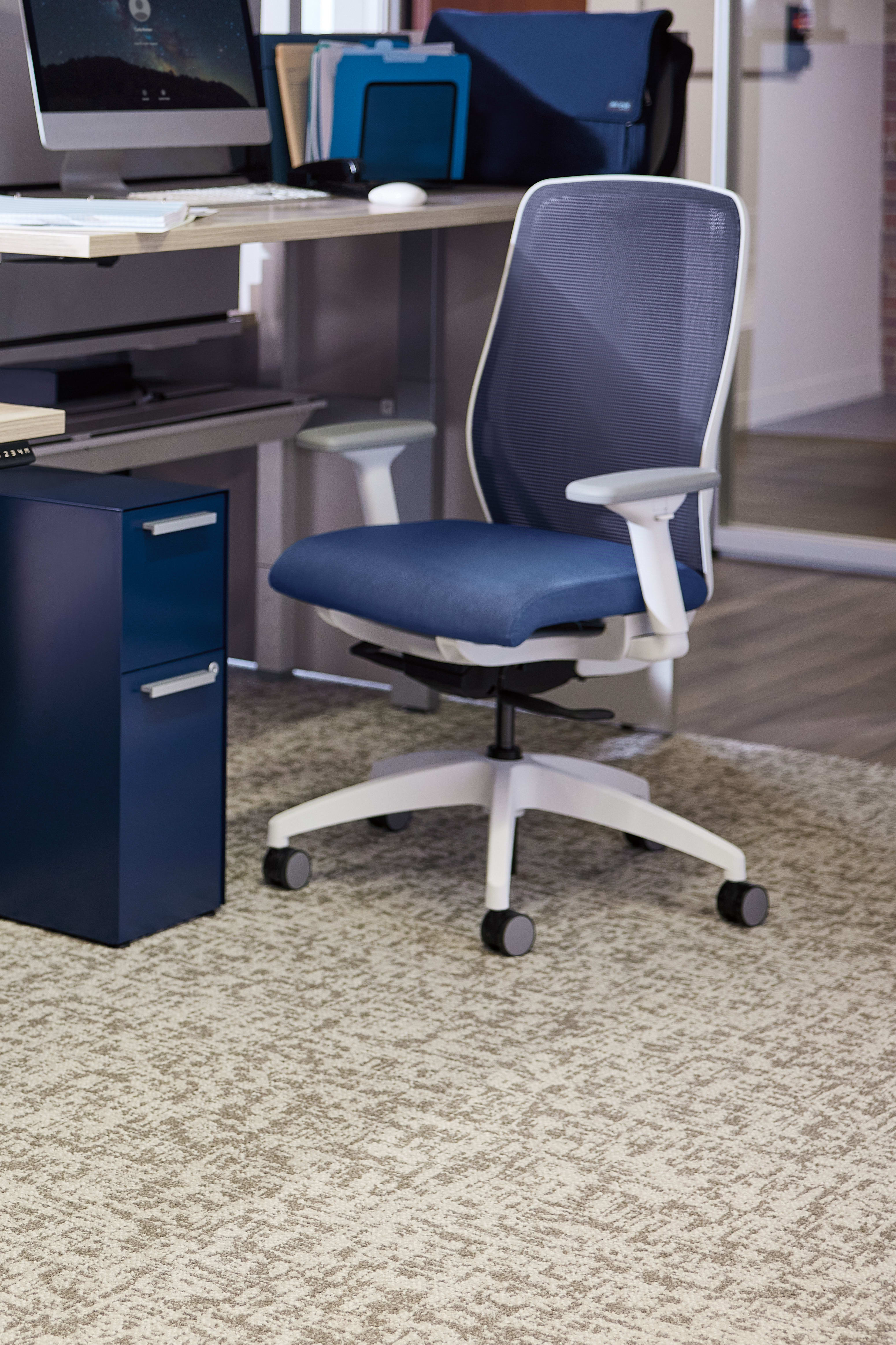 A modern and organized office workspace with a desk, computer, and various office supplies and equipment, including a comfortable-looking office chair.