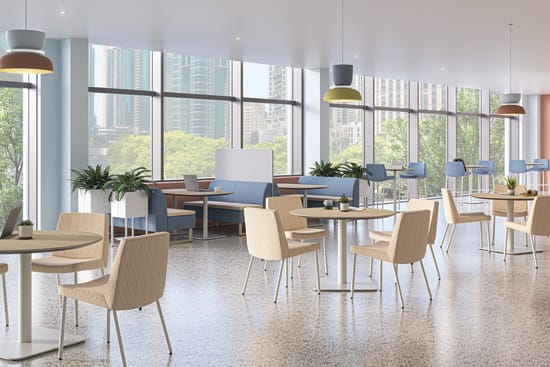 A bright, modern workplace cafeteria with floor-to-ceiling windows, round wooden tables, upholstered chairs, blue booth seating, and colorful pendant lights overlooking a city skyline.