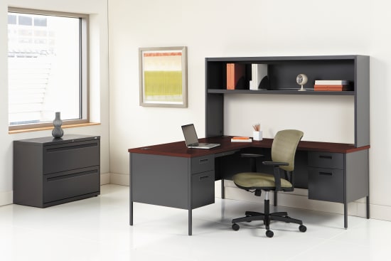 A modern and minimalist home office setup with a black desk, shelving unit, and a comfortable office chair in a bright and airy room.