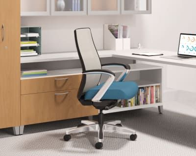 A modern, minimalist office workspace with a comfortable-looking office chair, shelves filled with books and documents, and a laptop on the desk.