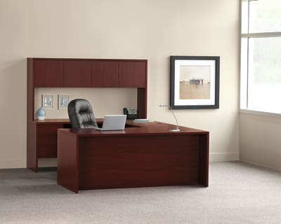 A modern and minimalist office workspace with a wooden desk, a laptop, and a framed artwork on the wall.