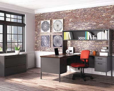 A modern and stylish home office with a brick wall, shelves, a desk, and a red office chair.