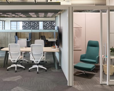 A modern and well-designed office space with glass partitions, comfortable chairs, and a cozy atmosphere.