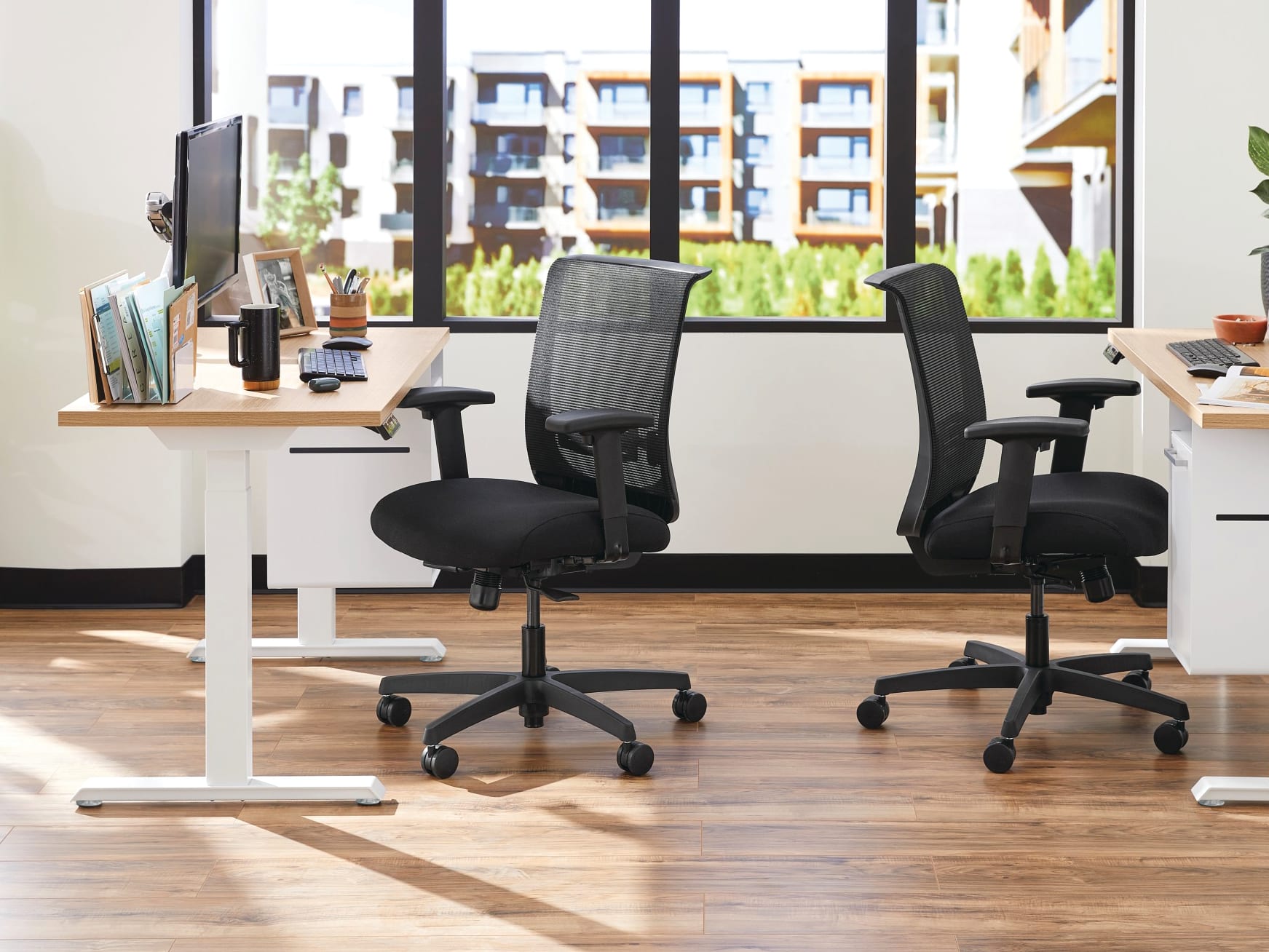 Two white Coordinate Height-Adjustable Bases paired with Coze desk tops and Convergence Task chairs in a small office setting