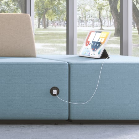 Tangram soft seating with power capabilities charging a tablet.