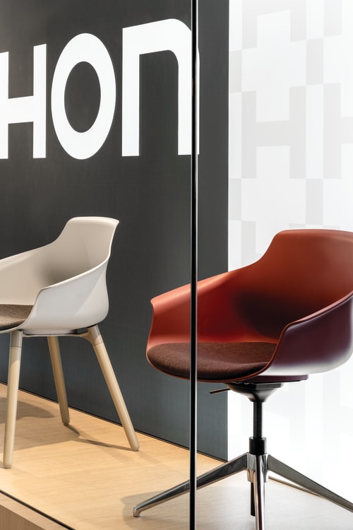 Display platform featuring a curated range of molded shell chairs with upholstered seats, presented on a raised wood base with mixed leg styles including wood, swivel, and four-star bases.