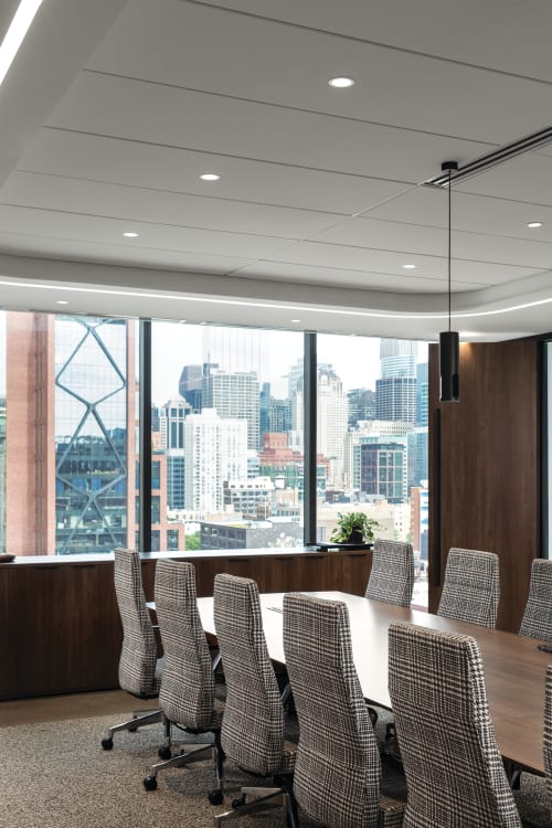 Conference seating area with upholstered rolling chairs, lounge sofa with cushioned seating, and compact side tables with wood tops and slim bases.
