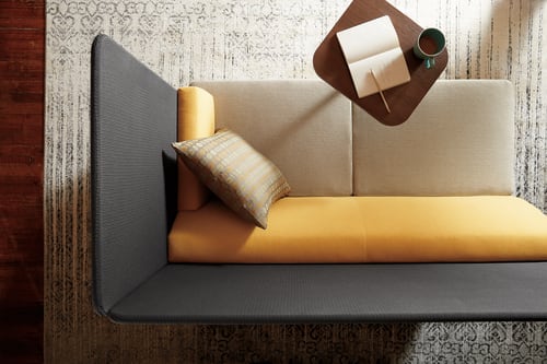 A cozy and modern living room setup with a gray sofa, yellow cushions, and various decorative elements on the wall and table.