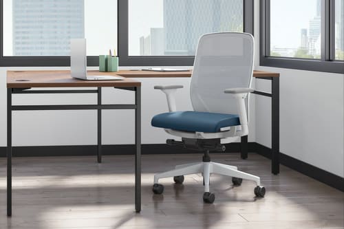 A  private office setting featuring a Mod desk and Nucleus task chair with white back and frame and blue seat.