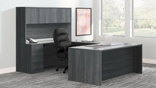 A modern and minimalist office workspace with a dark-colored desk, shelving unit, and a comfortable office chair situated in a bright, airy room with large windows.