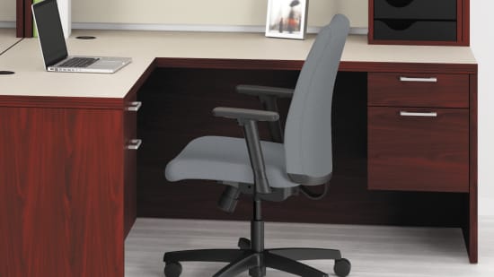 The image depicts a modern office workspace with a wooden desk, computer monitors, and office chairs arranged in a clean and organized manner. The background features large windows, allowing natural light to fill the space.