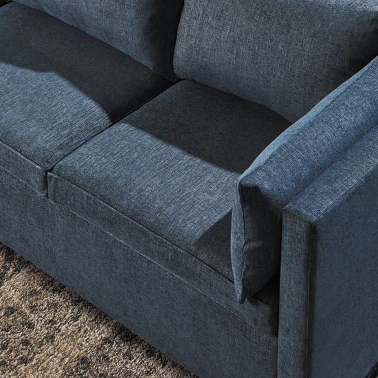 A dark gray upholstered sofa with distinct cushions and armrests sits on a carpeted floor.