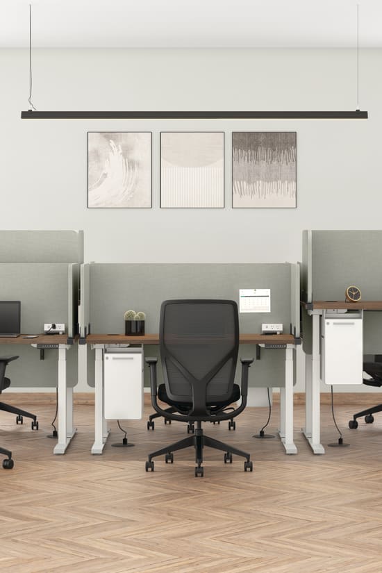 A modern and minimalist office space with white walls, wooden floors, and sleek black office chairs arranged around desks with potted plants and artwork on the walls.