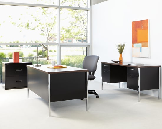 A modern and minimalist office space with sleek black furniture, large windows overlooking greenery, and vibrant artwork on the walls.