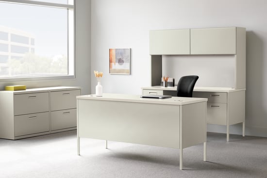 A modern, minimalist office space with a white desk, cabinets, and a framed artwork on the wall, set against a bright, natural light-filled background.