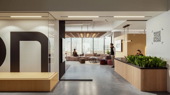 Lounge seating area with upholstered modular sofa, round coffee tables, and soft ottoman seating arranged for casual collaboration.