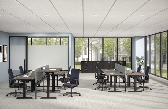 Modern open office with benching desks, task chairs, privacy panels, storage cabinets, and large windows with greenery view.