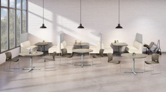 An open dining area with round tables, chairs, booth seating, hanging pendant lights, and large windows allowing natural light into the space.