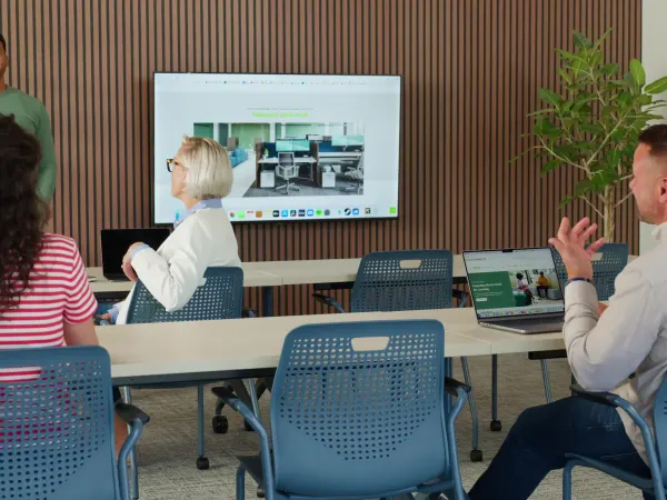 Small group of people in blue Etch chairs in a training setting with Motivate tables.