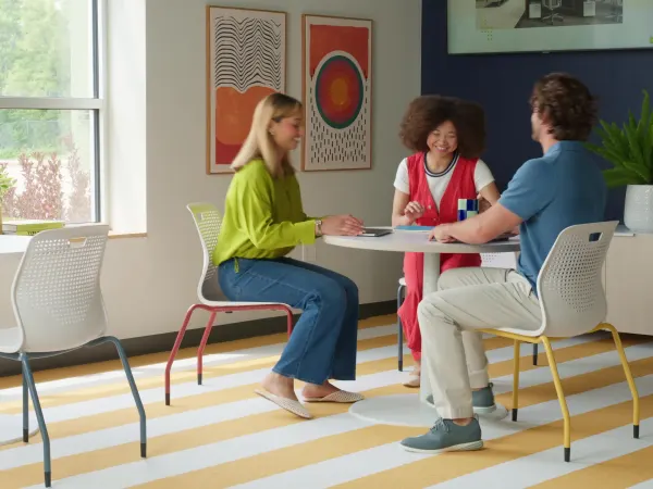 Group of people entering the room and sitting down at the Etch chairs and Between tables to collaborate.