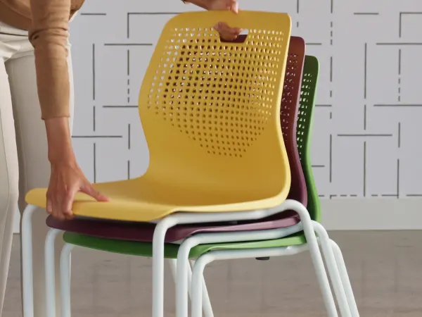 Etch chairs of assorted colors being stacked.