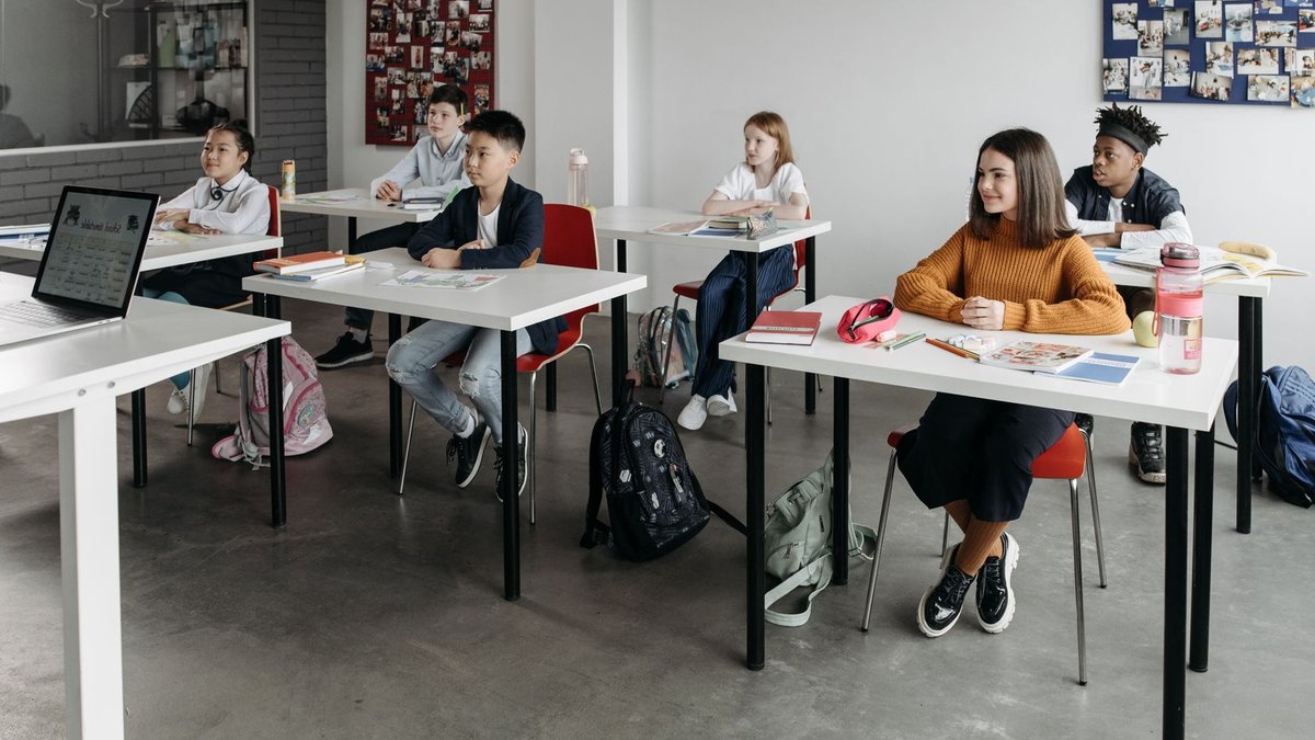Experts reframe chronic absenteeism as a school culture issue Diverse group of students learning attentively in a bright classroom setting.