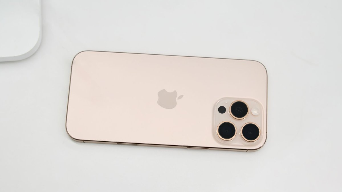 New machinery fabricates lighter, cost-effective glass units Gold smartphone featuring a triple-lens camera setup placed on a clean white surface.