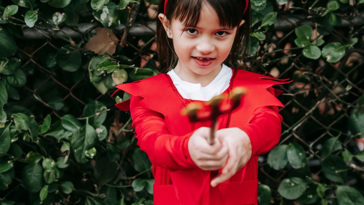 Onida revamps mascot to tackle India’s appliance trust crisis Crop adorable ethnic girl wearing red devil costume and pointing trident at camera while standing in park.