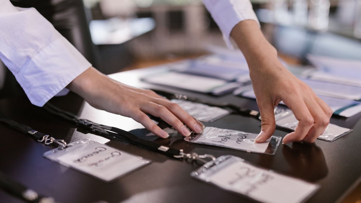 Close-up of hands arranging name tags on a conference table, preparing for a corporate event.