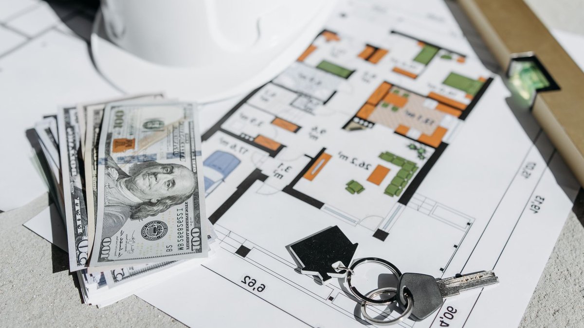 UK property owners face growing underinsurance risks Floor plan with cash, keys, and hard hat symbolizing real estate investment and property planning.